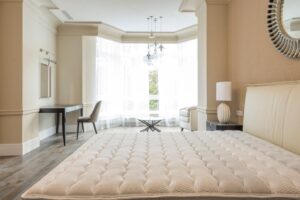 Materassi in lattice naturale: come scegliere e quali benefici apportano Elegant spacious bedroom with modern furniture, featuring large windows and abundant natural light.