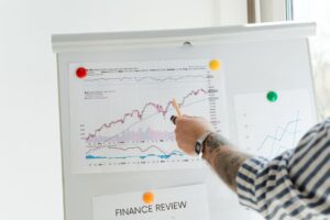 Analisi dei competitor SEO: dalle keyword mancanti alle decisioni editoriali A tattooed person pointing at finance charts and graphs on a whiteboard.